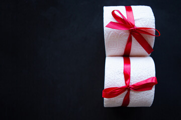 toilet paper rolls wrapped in gift bow on black background. Covid19 concept