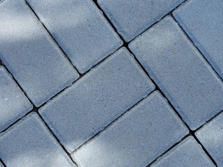 A close-up shot of gray stone paving slabs with shadows on it. Full frame - Powered by Adobe