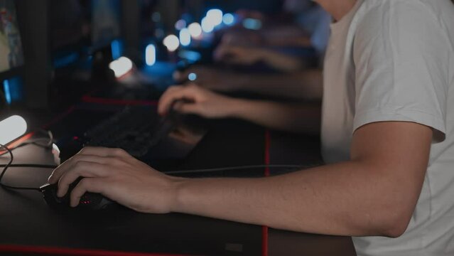 Player uses professional gaming mouse and PC keyboard with RGB lighting, mat. Cyber team in computer club. Skill. Esports tournament. Gamers play video game. Multiplayer online real-time strategy