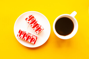 Delicious color cakes on a plate and coffee cup, top view. Bright yellow background, minimal...