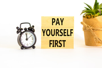 Pay yourself first symbol. Concept words Pay yourself first on beautiful wooden blocks. Beautiful white table white background. Black alarm clock. Business and pay yourself first concept. Copy space.