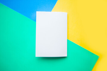 White mockup blank on geometric blue, yellow and green background