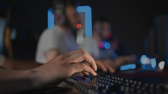 Cyber sport tournament at computer club E-sport championship. Fingers press keys on gaming keyboard close up. Left-handed team gamer plays video game on PC. Multiplayer online real-time strategy RTS