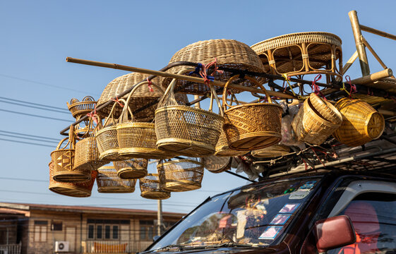 A low-level view of woven bamboo baskets and other things hanging for sale.