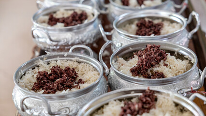 Close-up view of cooked rice packed in various aluminum pots.
