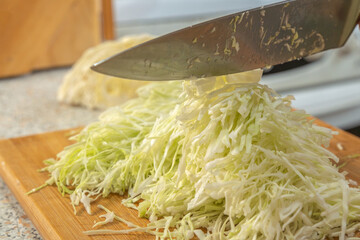 Thinly sliced white cabbage for making salad. Homemade food. Veganism and raw food diet concept.