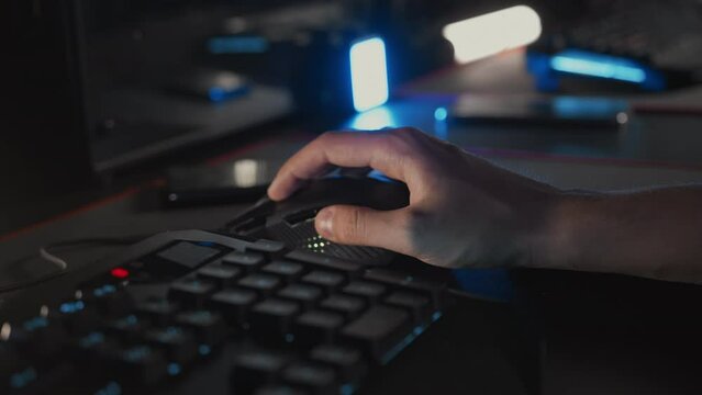 Gamer plays video game on PC at computer club, keyboard mouse RGB lightning animation close up. Skill. E-sport tournament championship Professional cyber sport. Multiplayer tactical shooter strategy