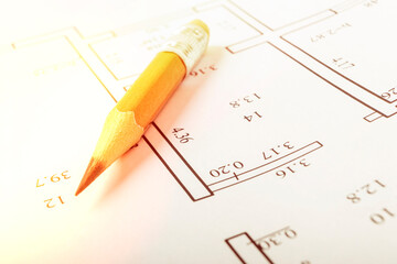 A graphite pencil lies on a piece of paper where there is a house project. close-up. there is a...