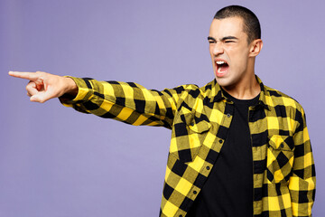 Young sad furious outraged middle eastern man he wear yellow shirt casual clothes point index finger aside scream isolated on plain pastel light purple background studio portrait. Lifestyle concept.