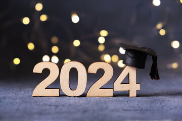 Class of 2024 concept. Number 2024 with graduated cap and bokeh lights.