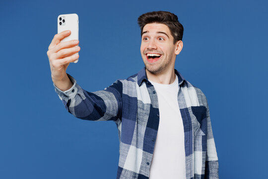 Young Caucasian man wear shirt white t-shirt casual clothes doing selfie shot on mobile cell phone post photo on social network isolated on plain blue cyan color background studio. Lifestyle concept.