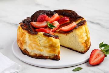 Fototapeta premium Basque san sebastian cheesecake on a marble background with strawberries