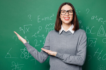 Young fun smart teacher woman wear grey casual shirt glasses point hands arms on empty blank area...
