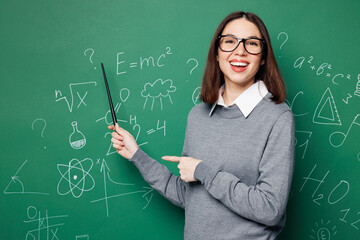Young teacher woman she wears grey casual shirt glasses hold pointer indicate on formula look camera isolated on green wall chalk blackboard background studio Education in high school college concept