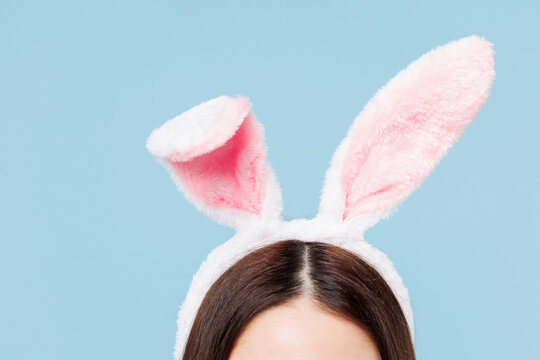 Close up cropped young Caucasian woman she wearing rabbit bunny ears isolated on plain pastel light blue cyan color background studio portrait. Lifestyle, celebration of spring Easter holiday concept.