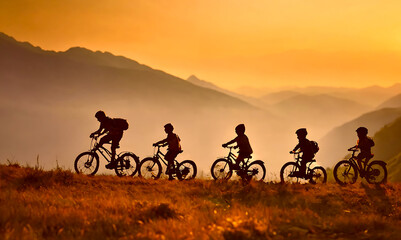 group of children - boys and girls. friends of black silhouette in sunrise on yellow evening sky, mountain background. grass. team of kids ride on bicycles. summertime season. summer nature.