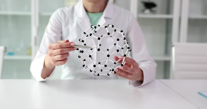 A woman holds a model of connection of molecules, a close-up. Creating a new formula, pharmacology