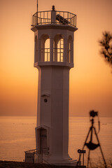Scenery of a lighthouse with an orange morning sky
