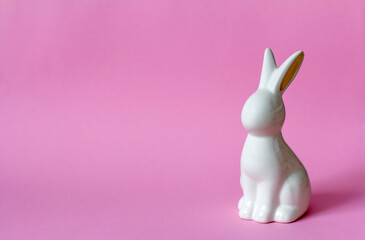 Ceramic Easter bunny on pink background, Easter minimalism concept with copy space.