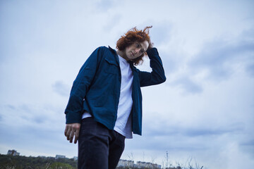 Youthful redhead with a thoughtful gaze against an overcast sky