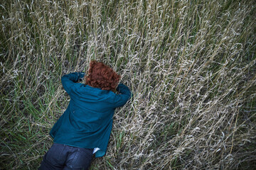 Redhead lying in dry grass, contemplating