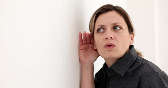 A business woman is eavesdropping through a wall, a close-up. Confidential information, curiosity