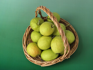 A basket of fresh fruit pears on a green background