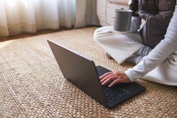 Closeup image of a woman drinking coffee while working on laptop computer at home