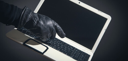 Hacker hand in a leather glove with a computer.