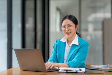 Asian businesswoman is sitting at a desk with a laptop in front of her