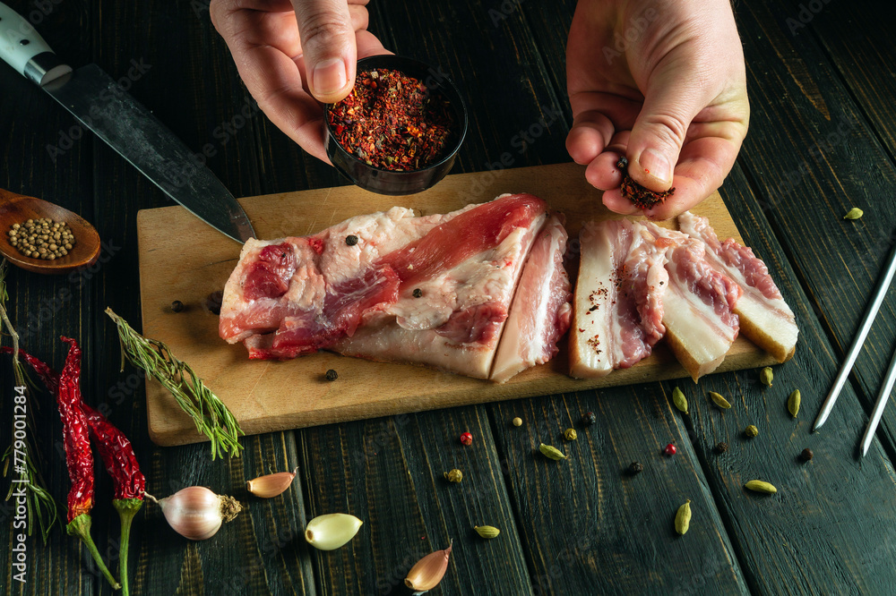 Wall mural Adding spices to lard by the cook hands. The concept of creating exquisite taste and aroma using seasonings.