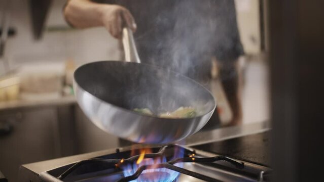 Close up of a chef cooking vegetables in a hot pan. Gastronomic french restaurant