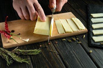 The chef uses a knife to cut milk cheese into thin strips for table setting. The concept of serving...