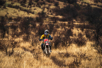 Professional enduro bike rider on action, front view of the motorcycle rider driving on the mountains