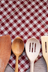 household items, wooden kitchen utensils on red and white tablecloth, place for text and logo