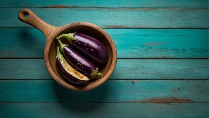 An aesthetically pleasing setting displaying ripe purple eggplants neatly arranged in a wooden bowl on a blue wooden surface