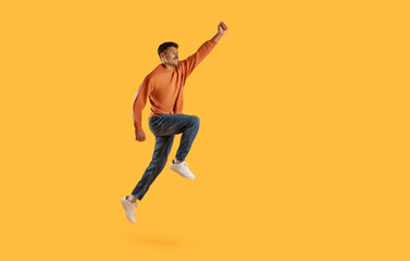 Fototapeta na wymiar Jumping man with raised fist on yellow