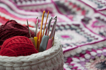 Crochet hooks of different sizes in a wicker basket with threads