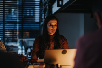 A group of business professionals collaborating in a creative office late at night to discuss project development, marketing strategies, and business growth.