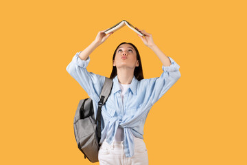 Funny pretty young woman holding book above her head