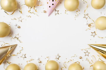 Fototapeta premium Fashion birthday party festive background with golden decoration from balloons, carnival cap and confetti stars on white table top view.