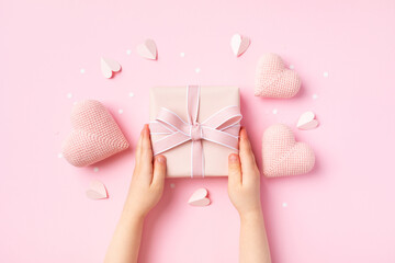 Child hands holding a gift or present box decorated with pink hearts for Happy mothers day. Holiday greeting card. - 779023077