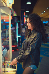 Woman standing in front of machine filled with stuffed animals indoor entertainment center