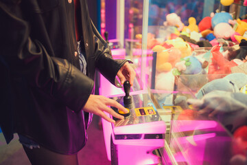 Person standing in front of machine filled with stuffed animals indoor entertainment center