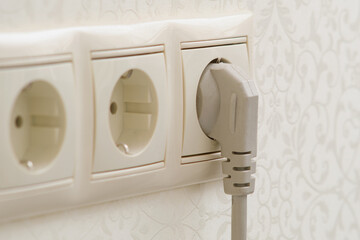 Plugs an electric cable into an outlet