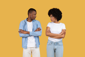 Two people with arms crossed, stern on yellow