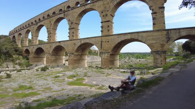 woman traveler gazes out at the UNESCO world heritage site, Pont du Gard, in the serene landscape of Provence in France.