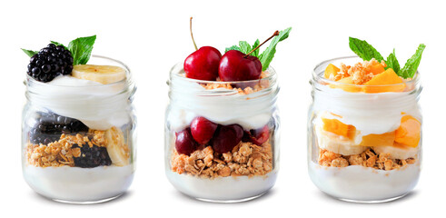 Variety of healthy greek yogurt and fruit parfaits in mason jars isolated on a white background. Blackberry banana, cherry and mango banana. - 779043478