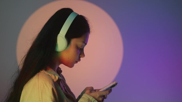 Profile portrait of charming dark-haired woman in massive headphones listening to music on isolated background