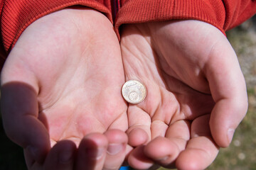 Hand holding one euro coins on the street.